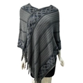 Detail shot of grey knitted shawl with blue diamond patterns and fringe hem on mannequin - Twill Gray