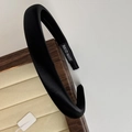 Close-up of a handmade black velvet headband elegantly placed on a wooden jewelry stand - Black