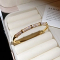 Macro shot of gold plated zircon pavé bangle resting on a cream velvet jewelry box - Micro-Pave Segmented Style (1#)