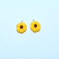 Colorful resin sunflower pendants with silver loops for DIY jewelry making on blue background - Yellow