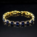 Detail of gold bracelet with alternating blue square and clear round zircons on black surface - Gold Plated Blue