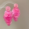 Close-up of pink layered shell fringe earrings displayed on a transparent stand - Pink Long Dangle