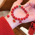 Detailansicht eines roten Achatperlenarmbands mit goldenem Schaukelpferd-Anhänger am Handgelenk. - Hohles Pony Stil 4 (9#)
