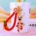Detail of snake keychain with sparkling rhinestones, golden alloy, and red woven strap - Red Lucky Rope + Red Snake