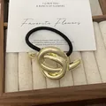 Punk style metallic gold knotted hair cuff with a black elastic hair tie on wood tray - GD438 Gold Smooth Knot