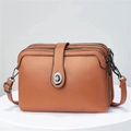 Detail view of brown pebbled leather crossbody bag with triple zippers and metal clasp - Earthy Yellow
