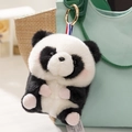 Cute panda plush keychain with golden ring and striped ribbon on a stylish bag - Panda