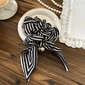 Detail eines schwarz-weiß gestreiften Haargummis mit eleganter Schleife und Perle - Schleife-Band-Stil / Schwarz Gestreift
