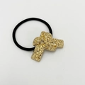 Detaillierte Makroansicht des goldenen Kreuzanhängers mit Hammerschlag-Textur auf Haargummi - Sandgold Typ 4