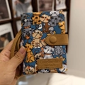 Blue fabric tri-fold wallet with cat pattern and brown leather strap held by hand - Handheld Colorful Cat Pattern