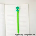 Bolígrafo de dinosaurio animado en color verde con adorno de goma sobre libreta - Dinosaurio