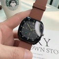 Detail of square quartz watch with black dial and brown silicone strap in a casual setting - Brown