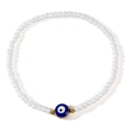 Ethnic white seed bead bracelet with blue evil eye charm and golden accents on white background - White