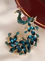 Macro detail of a golden peacock brooch featuring blue crystals and rhinestones - Blue Green Gemstone Peacock Style