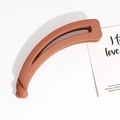 Detail of a matte clay red banana hair clip with an open-curved hollow design and twist lock - Orange