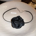 Detailansicht eines schwarzen Rosen-Chokers aus Stoff auf einem weißen strukturierten Teller - Schwarze Blume