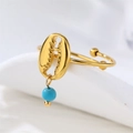Primer plano de un anillo de concha calada dorada con una cuenta turquesa azul - Azul/R00890G-B