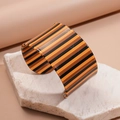 Detail van een brede acryl C-vormige armband met oranje en bruine strepen op steen - Bruine verticale strepen