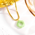 Detailed close-up of golden snake chain and light green acrylic flower pendant with texture - Yellow-Green