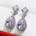 Detailed view of teardrop halo earrings featuring emerald green stones and cubic zirconia - White Zirconia