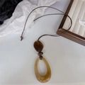 Collier en résine rétro avec anneau ovale ambré et perle marron sur cordon tressé - Design Ovale / Marron Ambré