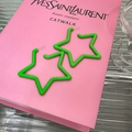 Primer plano de aretes de estrella verde mate sobre un libro rosa con sombras - Verde