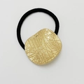 Black elastic hair tie with textured golden irregular metal charm on white background - Matte Gold - Grid Round