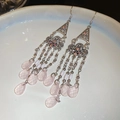 Detailopname van lange boho-oorbellen met roze druppelparels en zilveren metalen elementen - Roze