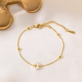 Detailed macro of a gold flower necklace featuring white pearls on a soft silk background - Single-Flower Pearl Bracelet / Gold