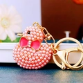 Charming duck keychain featuring pink faux pearls, a red enamel bow, and golden ring - Pink Pearl Duck