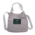 Grey canvas bucket bag with green woven label and adjustable crossbody strap - Gray