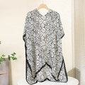 Detailed close-up of a floral print satin shawl with armholes and black hem piping - One Size / Black and White Rose