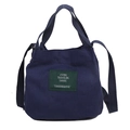 Navy blue canvas bucket tote bag with adjustable shoulder strap and green patch label - Dark Blue