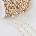 Beige cylindrical resin beads with gold metal spacers on a spool for DIY jewelry making - 1m / Beige