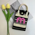 Detail of striped knit phone bag featuring a pink letter M and cream faux leather handle - Letter M-Black Stripe