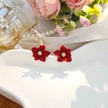 Macro shot of red floral earrings with golden pistils on an elegant ceramic plate - Red