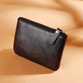 Black lychee pattern PU leather coin purse with zipper closure on warm fabric background - Black