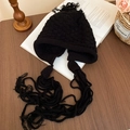 Dettaglio del cappello nero a maglia grossa con paraorecchie e lunghe nappe intrecciate - Cappello in maglia con paraorecchie e nappe / Nero