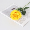 Artificial yellow velvet rose with green stem placed on an open magazine on a white table - Large Velvet Yellow