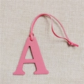 Pink lychee grain leather letter A bag charm with matching strap on linen background - Letter A Pink