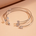Detail van drie roségouden open armbanden met zirkonia in de vorm van sterren en druppels - Armband - Zilver - Witte Zirkonia (3-delige set)