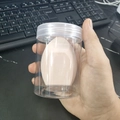 Pink giant egg-shaped makeup sponge in a clear storage jar for makeup blending - Cylindrical Box / Nude