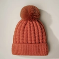 Detail of caramel knit beanie with rib pattern, metallic glitter and faux fur pompom - One Size / Rust red