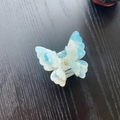 Detailed close-up of blue marble pattern 3D butterfly hair claw with gold spring - Iridescent Blue White