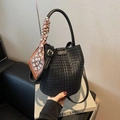 Black woven bucket bag featuring a decorative silk scarf on the top handle - Black