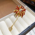 Dettaglio della spilla a fiore rosso con placcatura in oro e zirconi bianchi - Spilla a forma di fuoco d'artificio dorata in smalto rosso