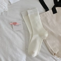 White ribbed crew socks in minimalist Japanese style laid flat on a white linen surface - One Size / White