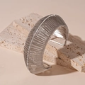 Nahaufnahme eines silbernen breiten geflochtenen Metallarmbands auf Steinsockel - Silber