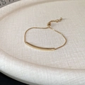 Minimalist gold plated bangle featuring a polished curved bar and adjustable box chain - Gold
