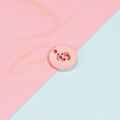 Macro shot of rose gold round pendant with footprint cutout on pink and blue background - Rose Gold